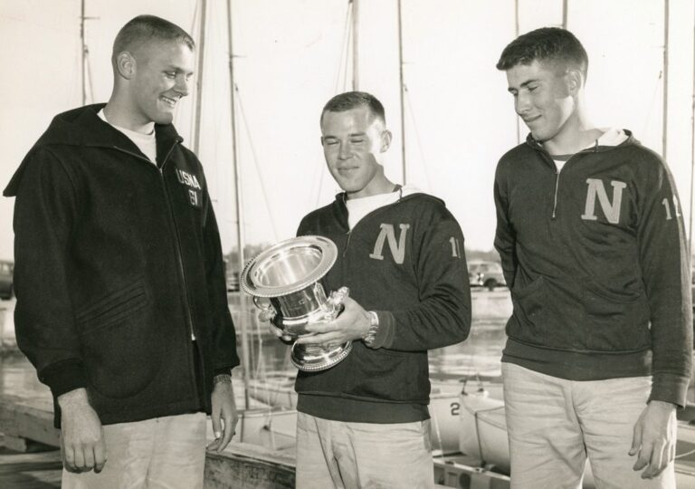 Butch Ulmer, Left, smiles with his Naval Academy friends as they hold a large silver trophy cup.