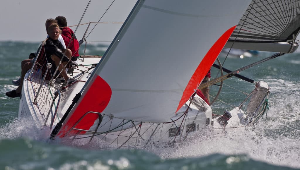 Photo showing a boat beating upwind with a storm jib with orange corners.