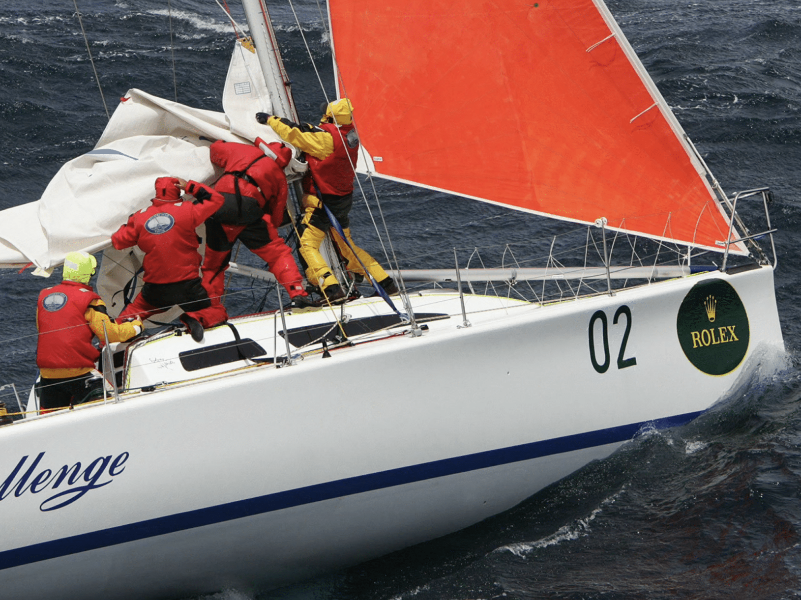 Image of a reefed mainsail and a bright orange storm headsail